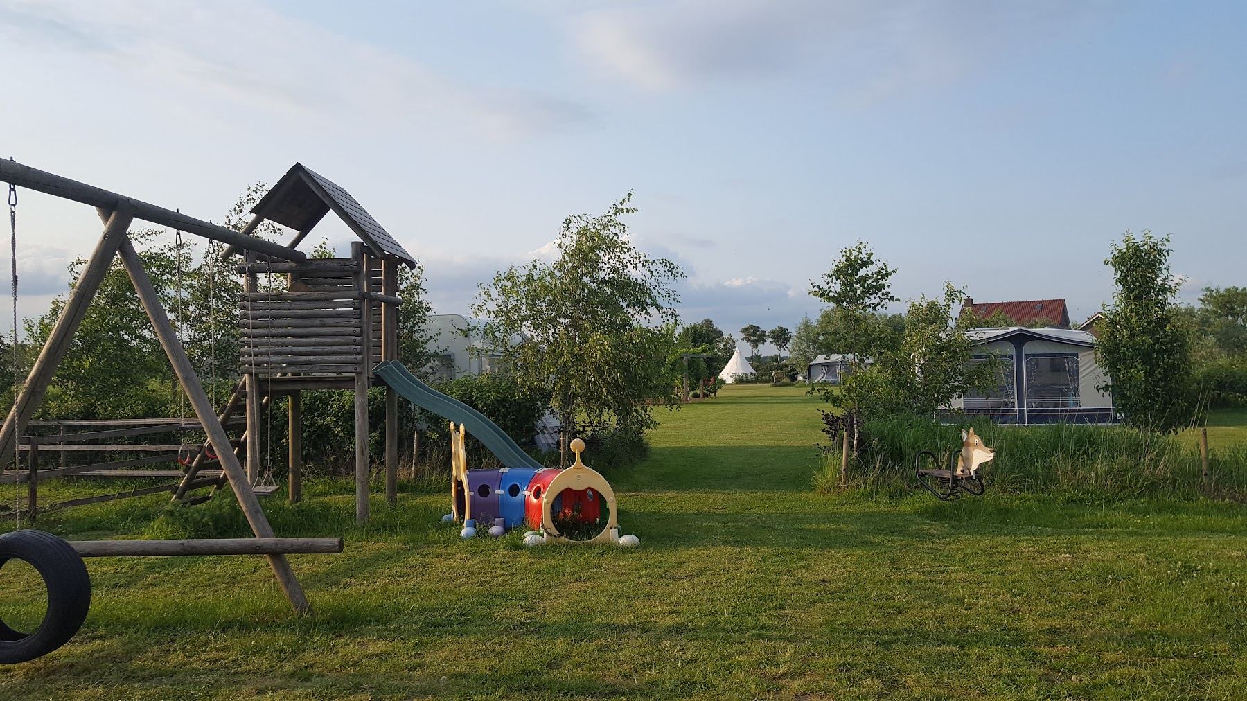Het speelveld met klimtoestel, glijbaan en schommel